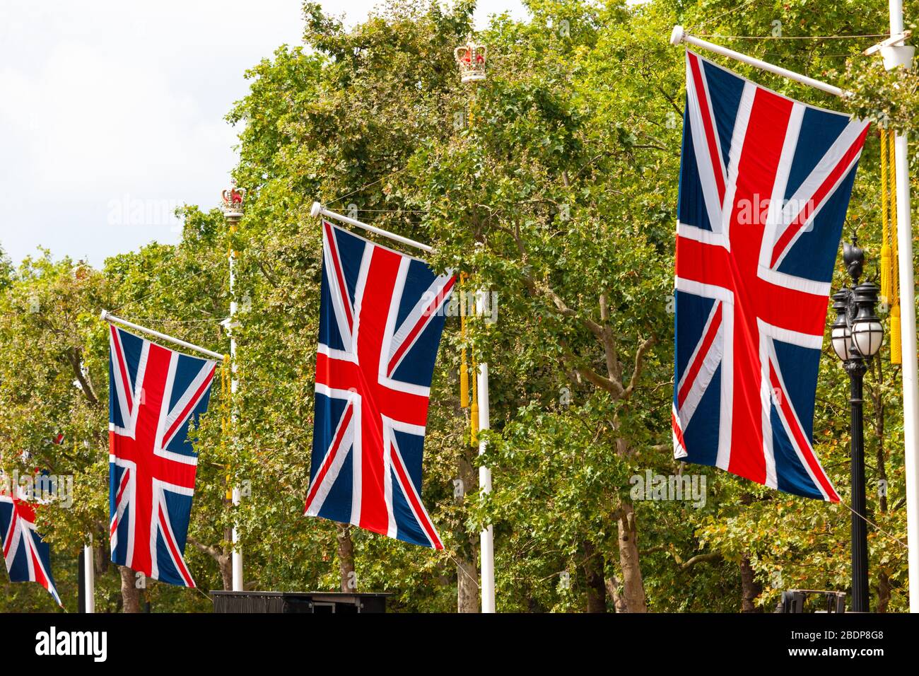 Grandi versioni dell'Union Jack appendono dalle aste di bandiera lungo il Mall nella City of Westminster, Greater London prima di un grande evento. Foto Stock