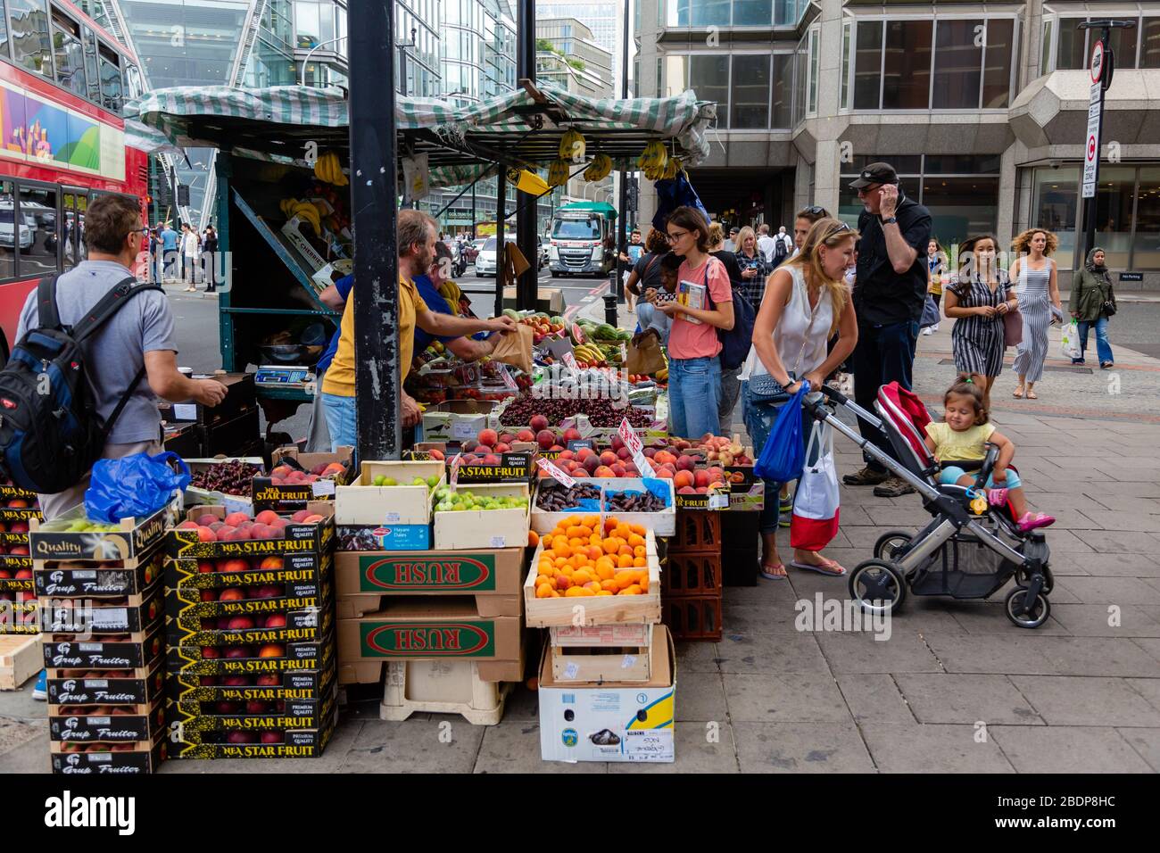 La gente del posto si ferma per raccogliere frutta e verdura da un venditore di strada presso il suo stand di prodotti nella città di Westminster, nella Grande Londra. Foto Stock