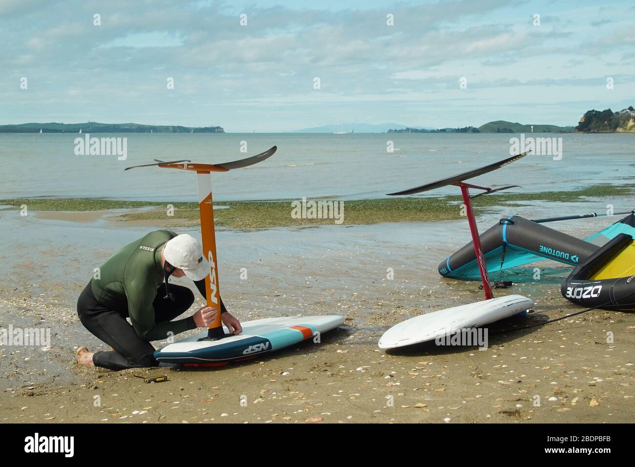 Due uomini preparano la loro attrezzatura per andare alare fliling usando le ali gonfiabili e le tavole da surf di aliscafo tenute a mano nel porto di Auckland. Foto Stock