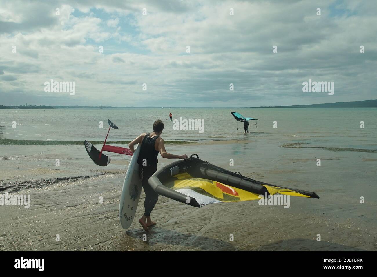 Due uomini preparano la loro attrezzatura per andare alare fliling usando le ali gonfiabili e le tavole da surf di aliscafo tenute a mano nel porto di Auckland. Foto Stock