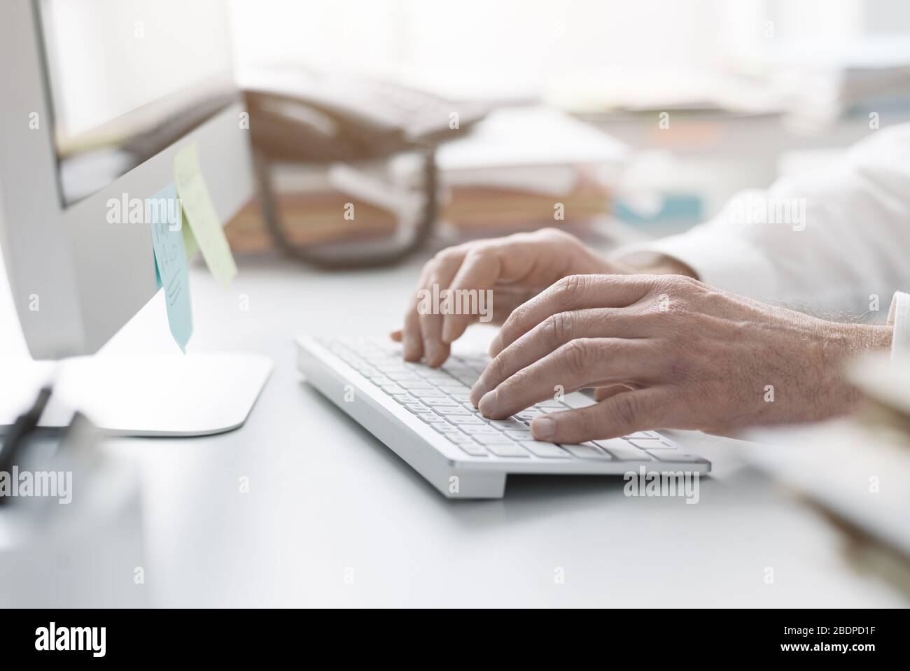 Uomo d'affari che lavora con il suo computer in ufficio, sta digitando sulla tastiera, mani vicine Foto Stock