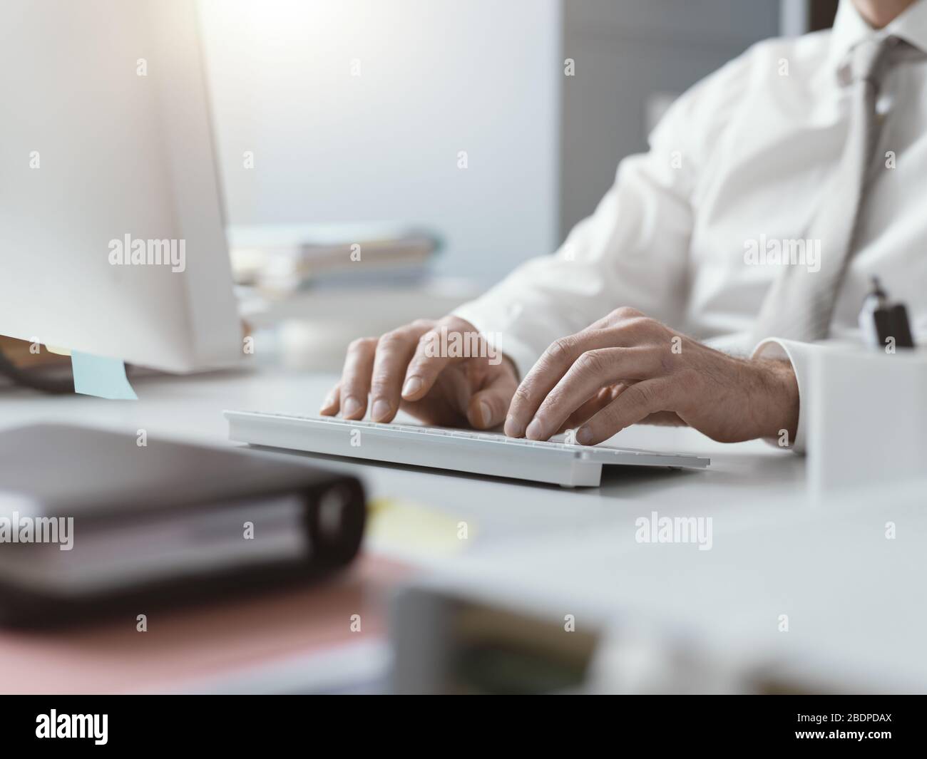 Uomo d'affari che lavora con il suo computer in ufficio, sta digitando sulla tastiera, mani vicine Foto Stock