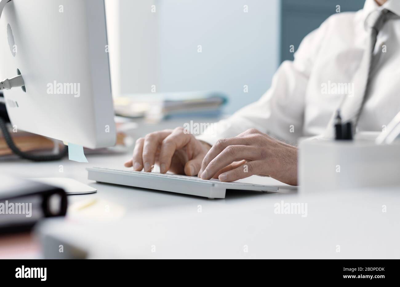 Uomo d'affari che lavora con il suo computer in ufficio, sta digitando sulla tastiera, mani vicine Foto Stock