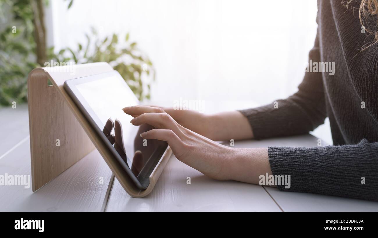 Donna che utilizza le app su un tablet digitale e navigazione sul Web, le mani si avvicinano Foto Stock