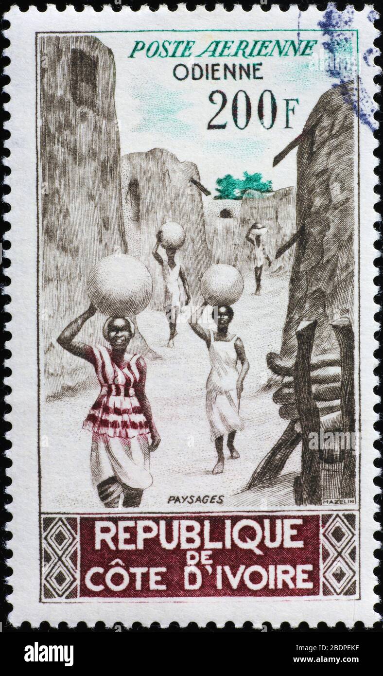 Donne che trasportano acqua sul vecchio francobollo africano Foto Stock