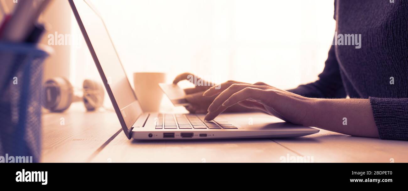 Donna che fa acquisti online utilizzando il suo laptop e una carta di credito, mani da vicino, e-commerce e online banking concetto Foto Stock