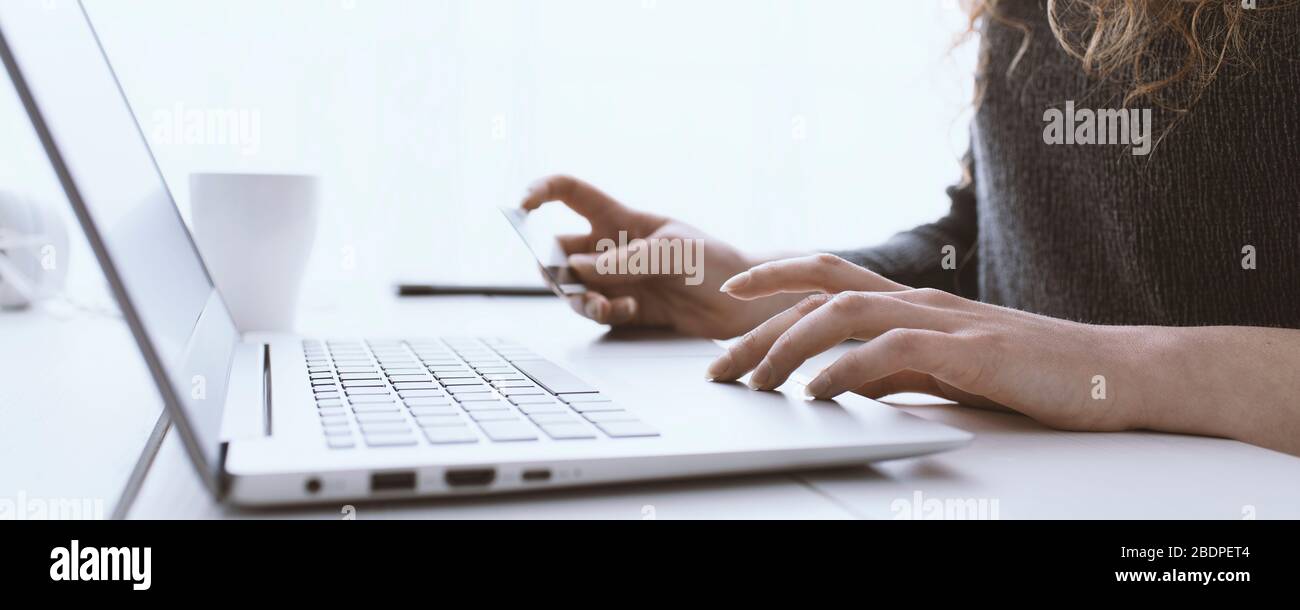 Donna che fa acquisti online utilizzando il suo laptop e una carta di credito, mani da vicino, e-commerce e online banking concetto Foto Stock