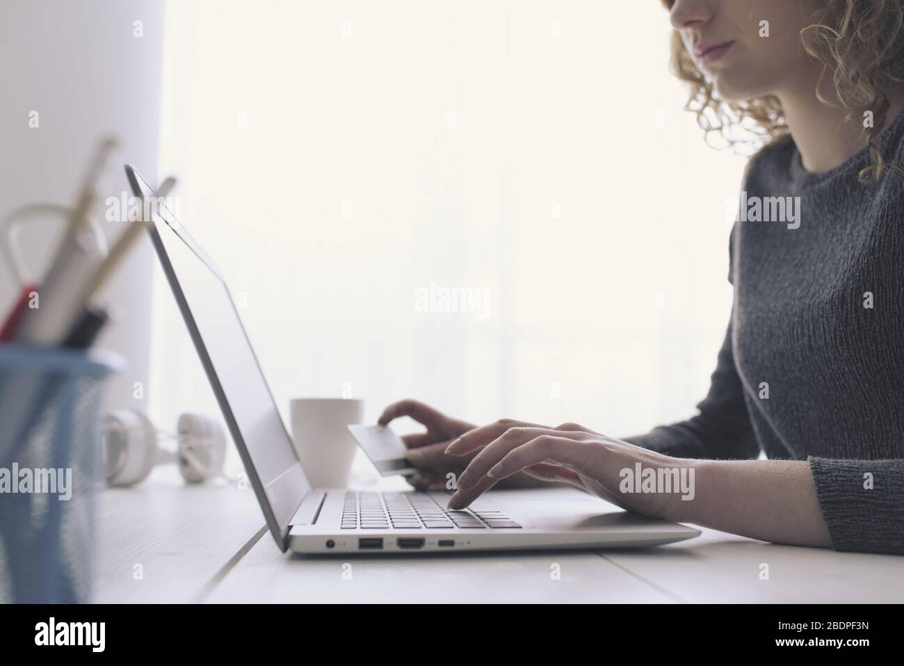 Donna che fa acquisti online utilizzando il suo laptop e una carta di credito, mani da vicino, e-commerce e online banking concetto Foto Stock