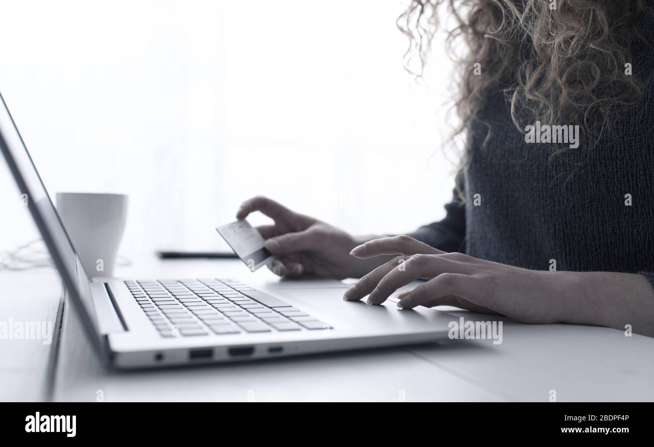Donna che fa acquisti online utilizzando il suo laptop e una carta di credito, mani da vicino, e-commerce e online banking concetto Foto Stock
