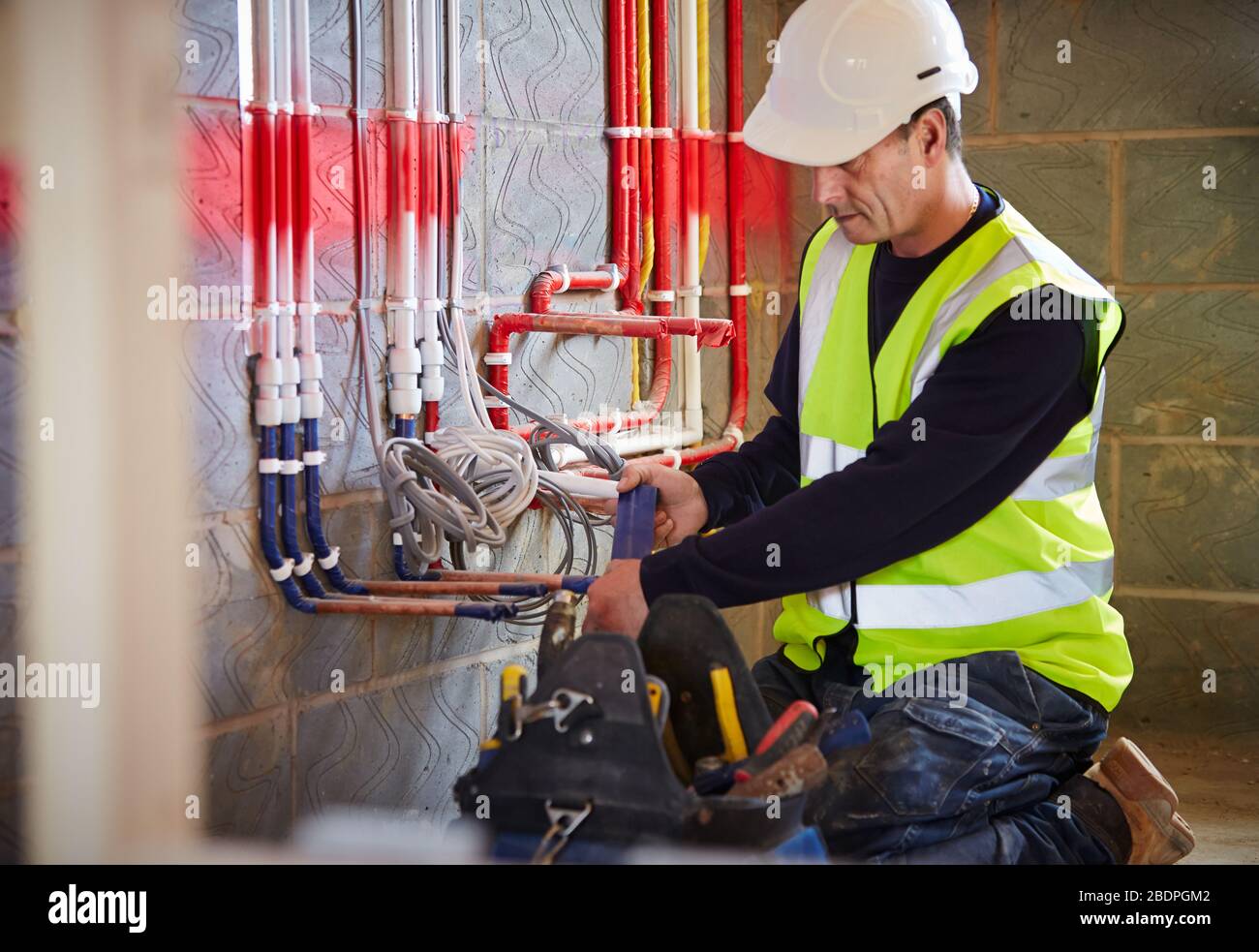 Elettricista al lavoro che installa il tubo per passare i cavi elettrici  nel cantiere Foto stock - Alamy