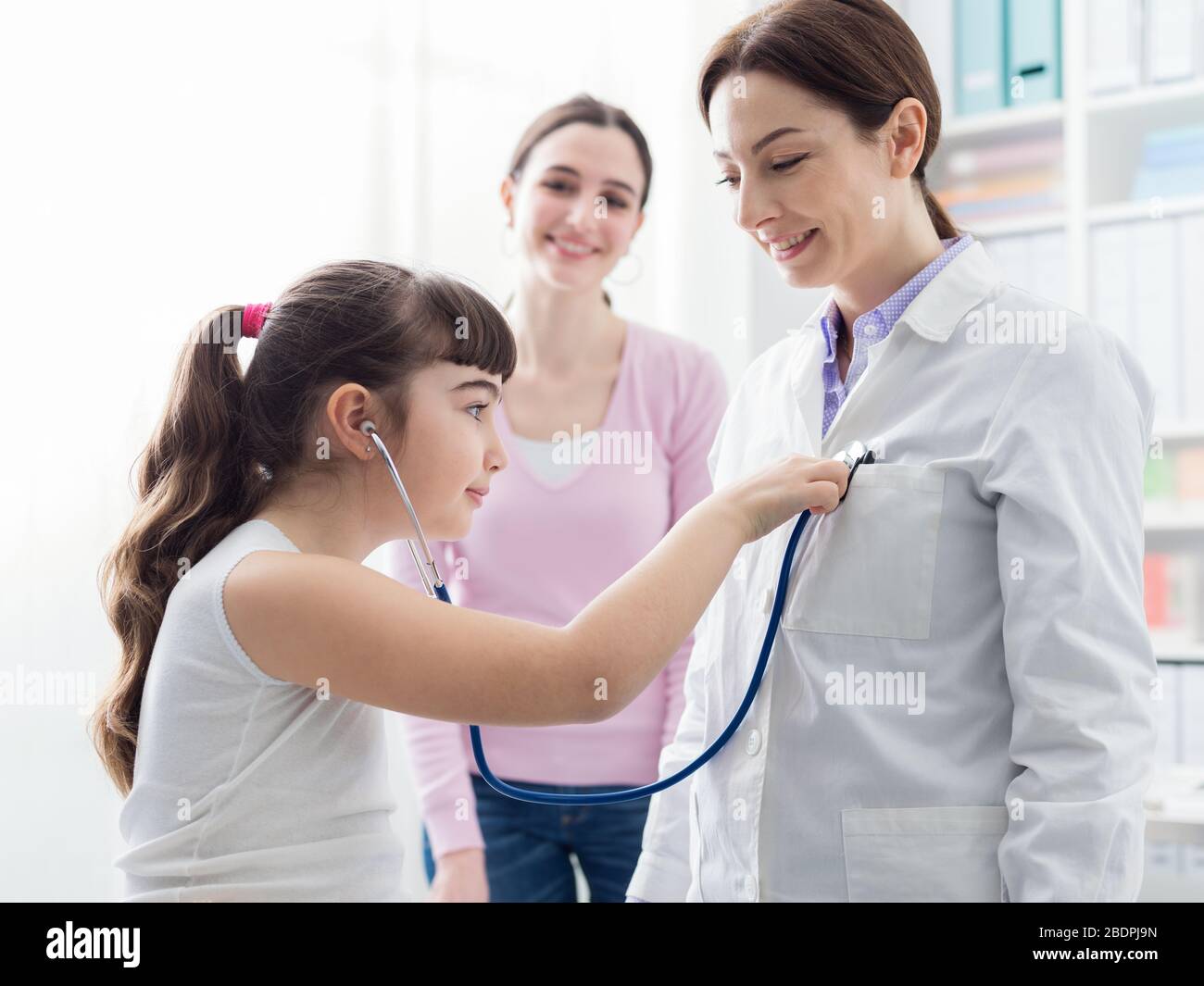 Medico amichevole che gioca con un giovane paziente durante una visita: La  ragazza sta esaminando il medico con uno stetoscopio Foto stock - Alamy