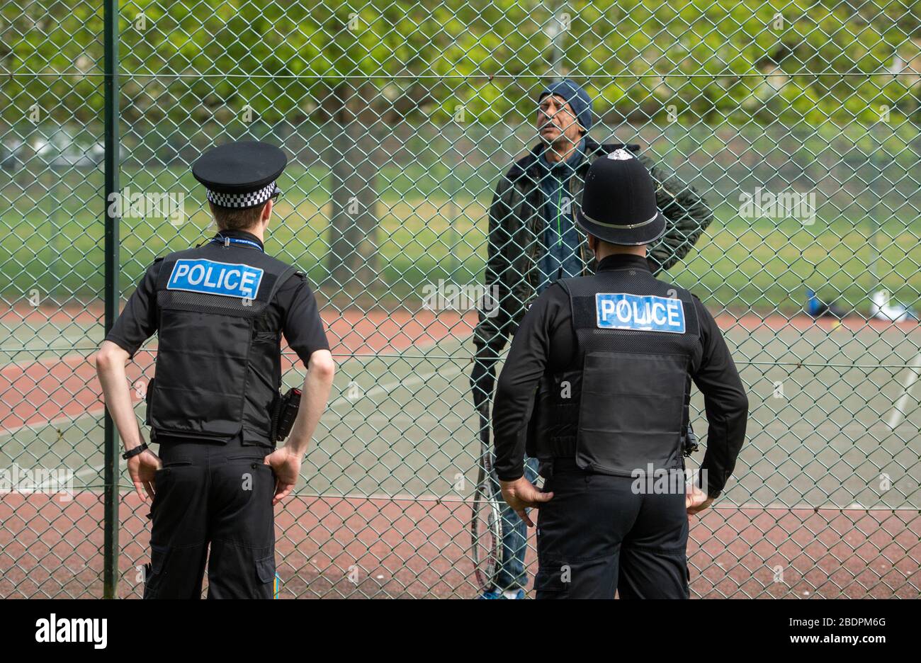Gli ufficiali di polizia parlano con un uomo che gioca a tennis a Northampton, come la polizia Northants annuncia che stanno rinforzando le loro forze di allontanamento sociale, mentre il Regno Unito continua a bloccarsi per contribuire a frenare la diffusione di Covid-19. Foto Stock