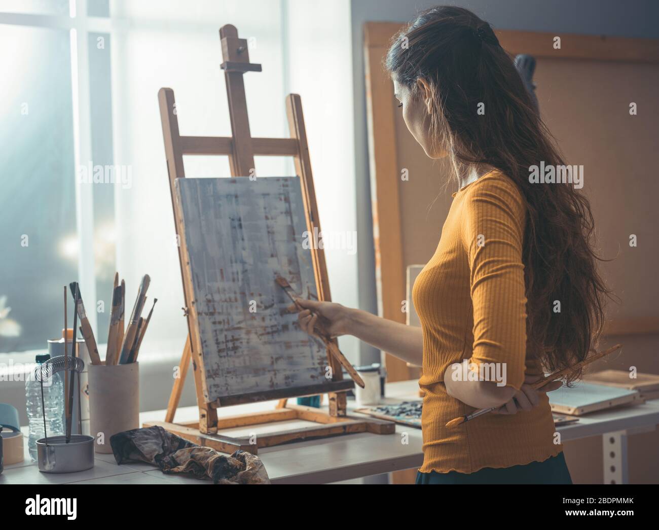 Giovane artista creativo che lavora su una pittura astratta nell'atelier Foto Stock