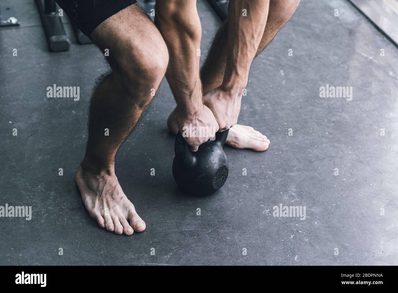 Uomo atletico che si esercita in palestra, sta facendo lifting con un kettlebell Foto Stock