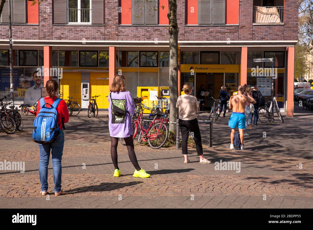 Focolaio di coronavirus/Covid 19, 8 aprile. 2020. Persone che si trovano in una lunga coda di fronte all'ufficio postale in piazza Sudermann, Colonia, Germania. Foto Stock