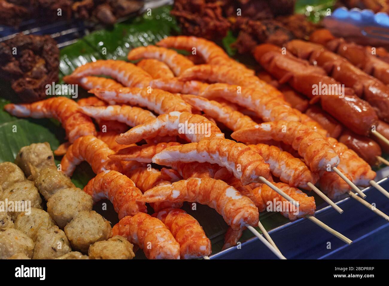 Gamberi, palle di carne e salsicce su bastoni in una teglia sul mercato alimentare di strada a Phuket, Thailandia, primo piano. Foto Stock