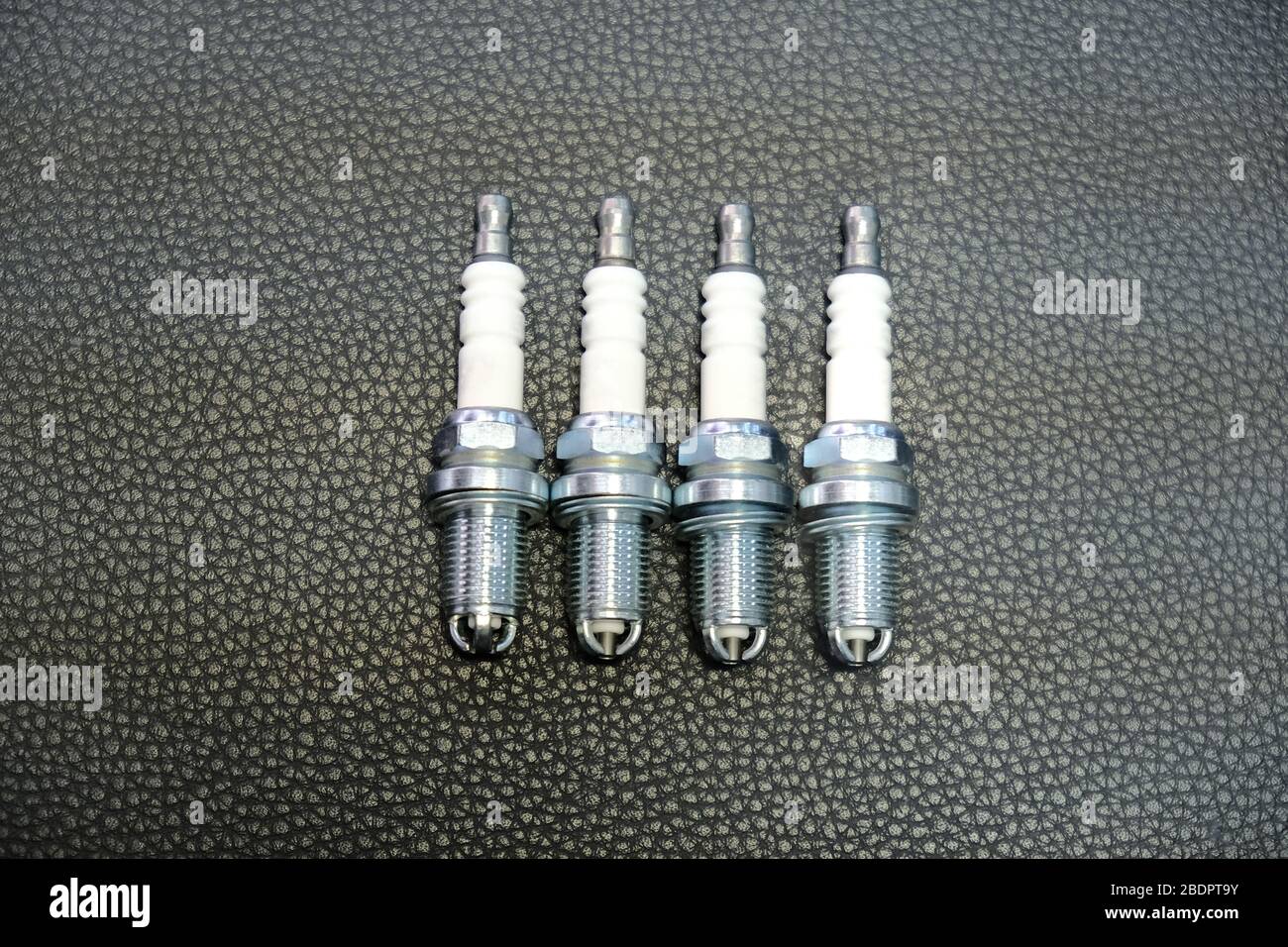 Quattro candele per auto su sfondo nero Foto Stock