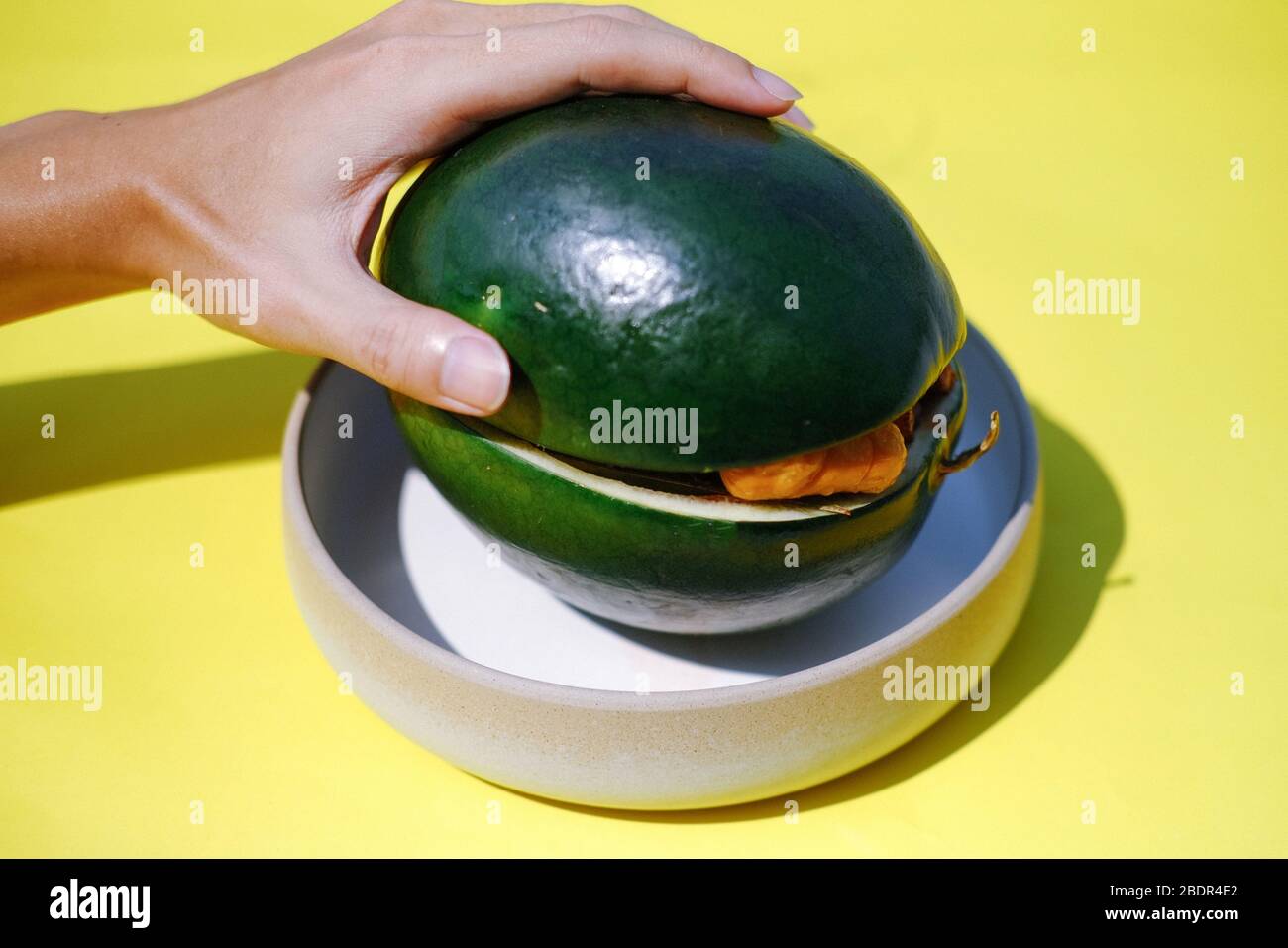 anguria come contenitore di cibo zero-waste su piastra con sfondo giallo Foto Stock