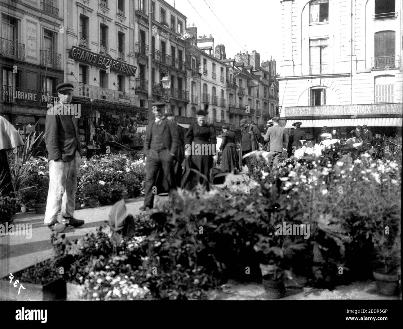 Vecchia Parigi Vittoriana storica: La gente passeggia attraverso un mercato dei fiori nel cuore di Parigi nel 1896 con un Grands Bazar Reunis sullo sfondo Foto Stock