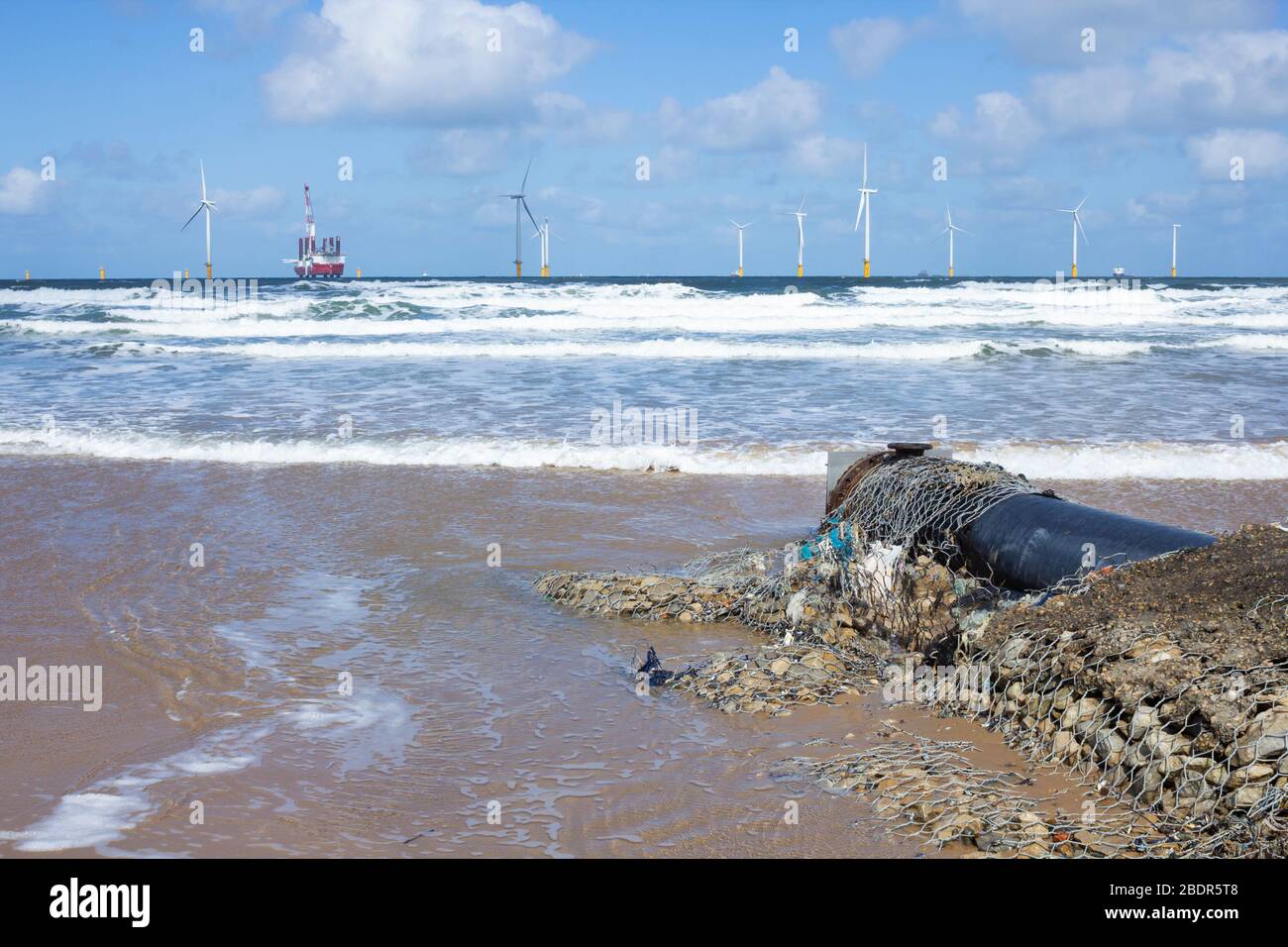 Tubo di deflusso di rifiuti sulla spiaggia di Coatham con Jack Up RIG, MPI Adventure, installazione di turbine eoliche offshore a Redcar, Inghilterra nord-orientale, Regno Unito Foto Stock