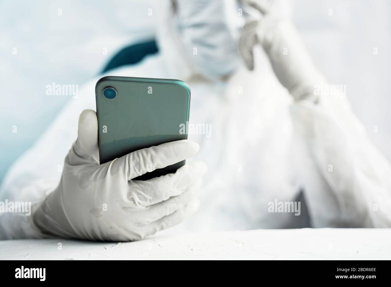 Donna persona si protegge da una pandemia globale e tiene un telefono nelle sue mani. Foto Stock