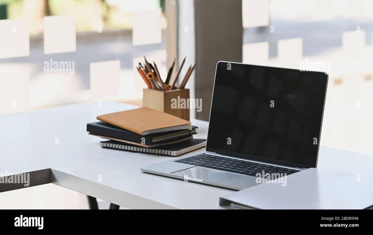 Computer portatile con schermo nero vuoto mettere sul moderno tavolo di  lavoro con portamatite in legno, pila di libri e documenti.  Ordinato/ordinato Foto stock - Alamy