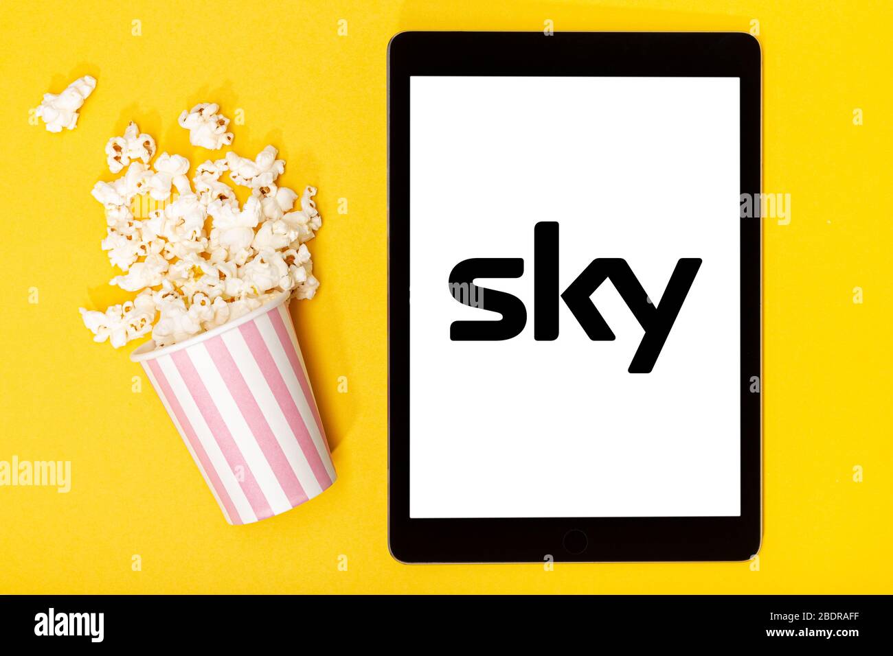 Galizia, Spagna. 9 marzo 2020; secchio e compressa di popcorn con logo SKY su sfondo giallo. Vista dall'alto Foto Stock