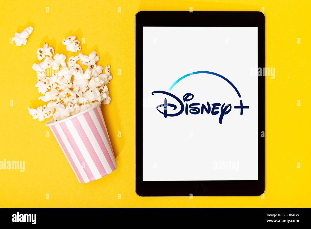 Galizia, Spagna. 9 marzo 2020; secchio e tablet Popcorn con logo Disney Plus su sfondo giallo. Vista dall'alto Foto Stock