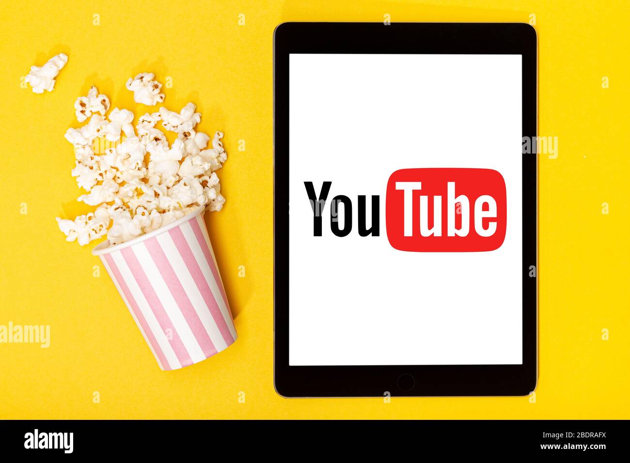 Galizia, Spagna. 9 marzo 2020; secchio e tablet Popcorn con logo YouTube su sfondo giallo. Vista dall'alto Foto Stock