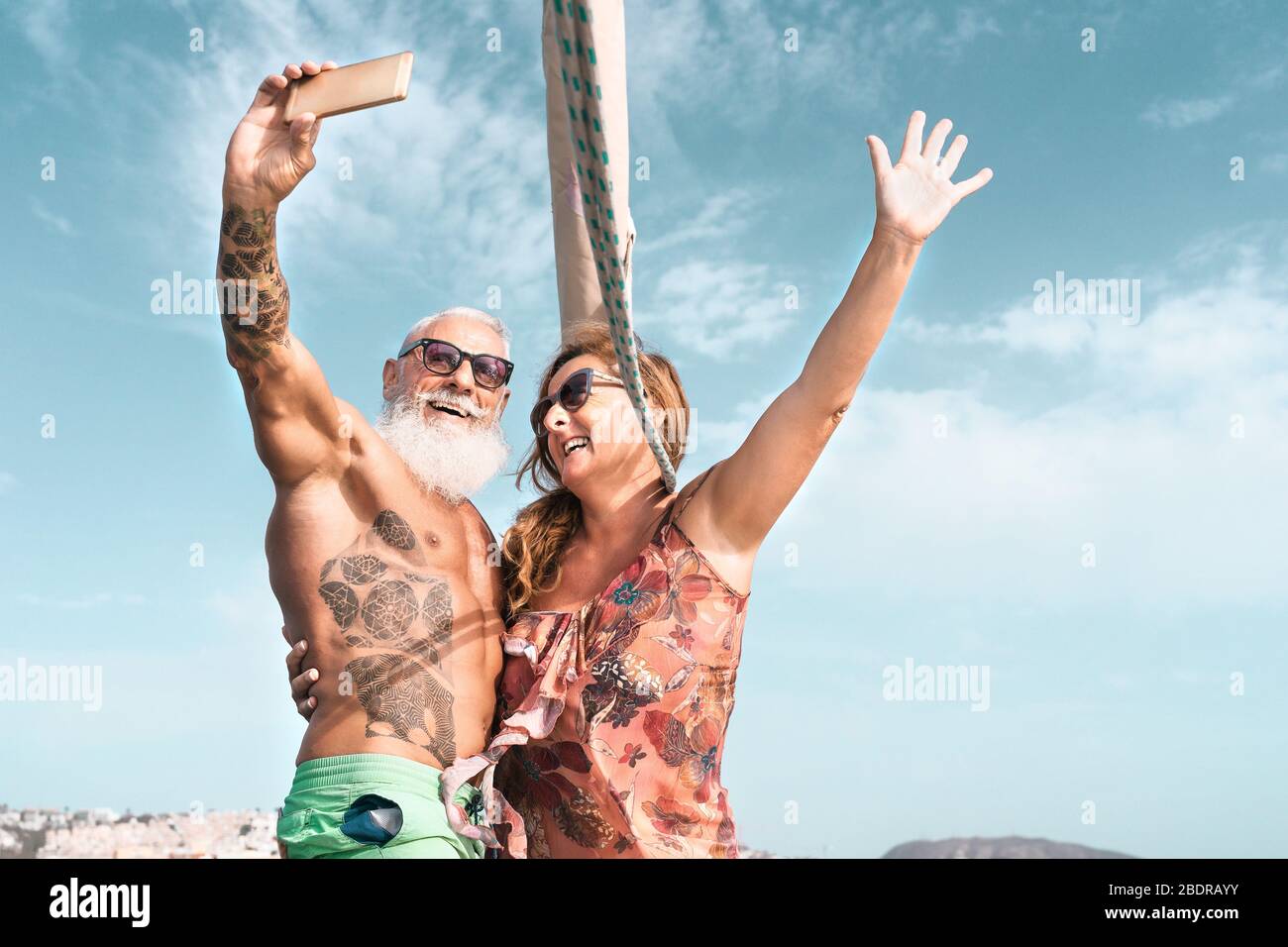 Coppia senior che prende selfie con smartphone mobile in vacanza a vela - felice gente matura che si diverte celebrare il matrimonio anniversario in barca Foto Stock