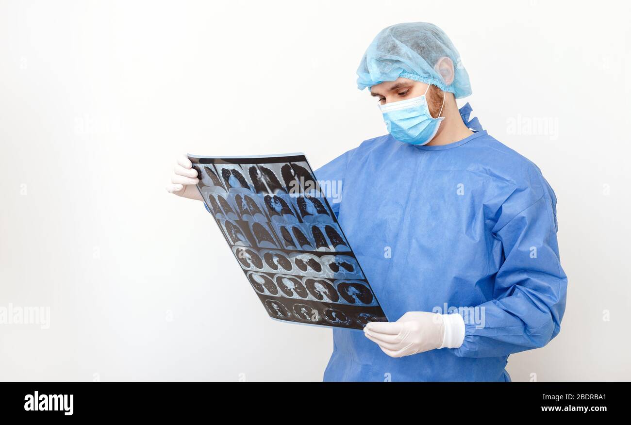 Medico chirurgo in controllo uniforme protettivo su pellicola di raggi X di risonanza magnetica polmoni scansione. Coronavirus Covid 19, polmonite, tubercolosi, cancro polmonare, respiratorio Foto Stock