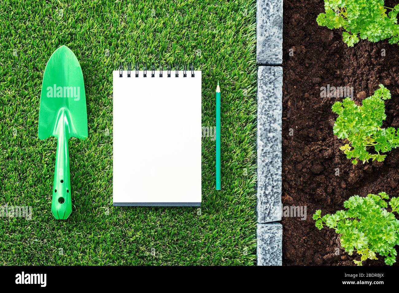 Elenco da fare del giardiniere: Blocco note vuoto, pala e piante che crescono sul terreno Foto Stock