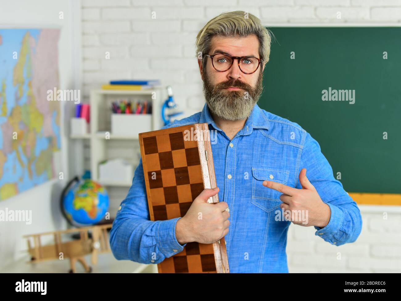 Scacchi club per studenti. Gioco logico per lo sviluppo del cervello. Scacchi in classe. Analisi della strategia di gioco. scacco mate. Hobby intelligente. Sviluppo logico. Tempo libero scuola. Uomo dito di puntamento. Foto Stock