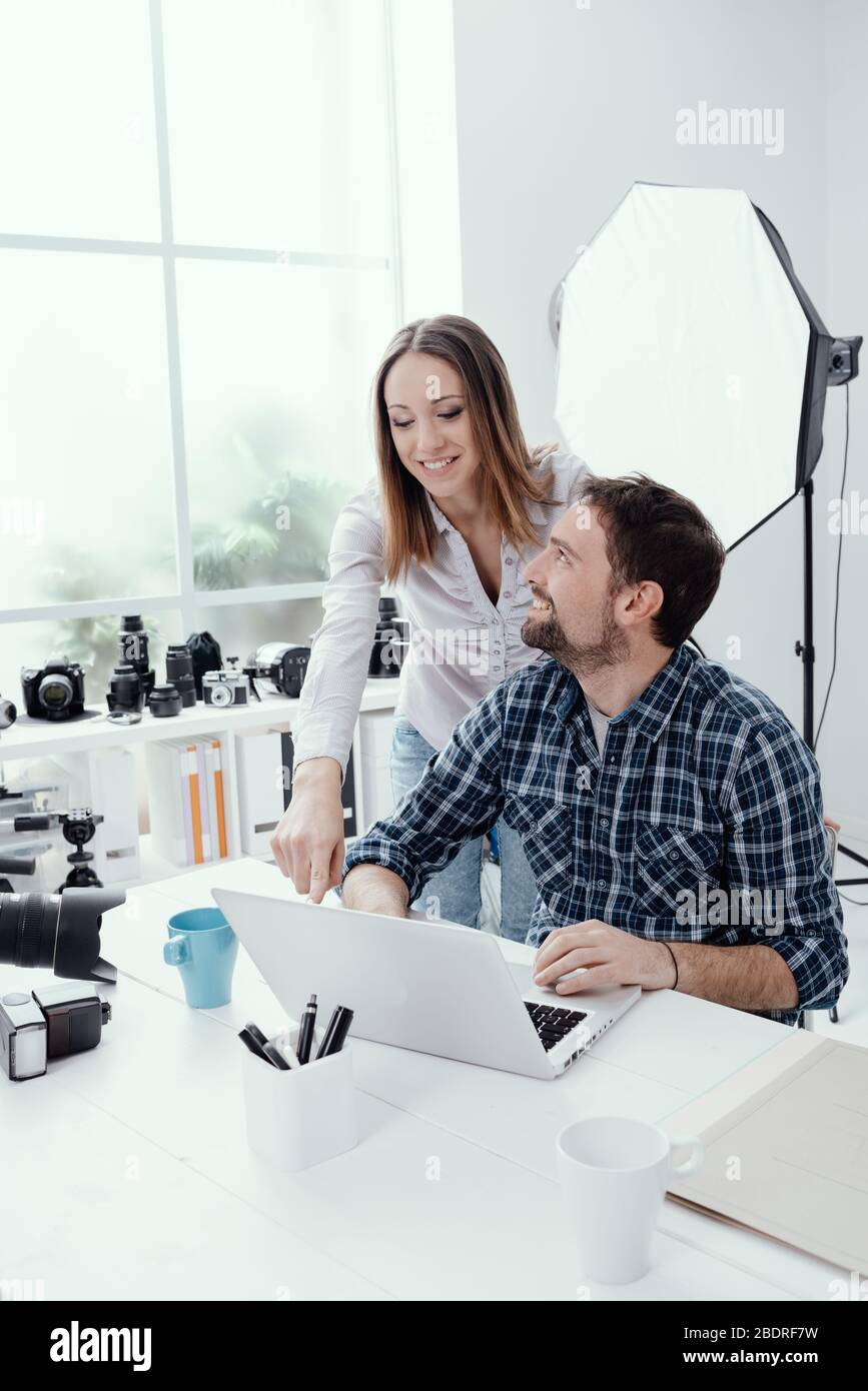 Fotografo e designer che lavorano insieme presso l'agenzia creativa, si connettono con un notebook Foto Stock