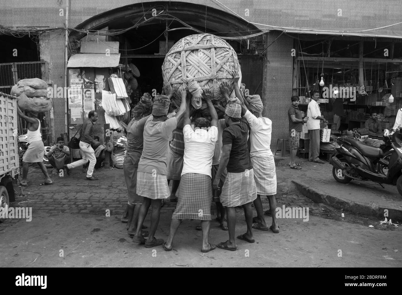 Lavoratori che raccolgono un carico pesante di merci a Koley Market, Kolkata, India. Foto Stock