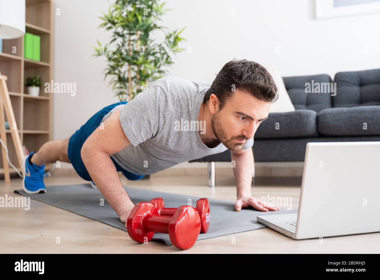 Allenamento di fitness mattutino di un uomo a casa guardando video tutorial  Foto stock - Alamy