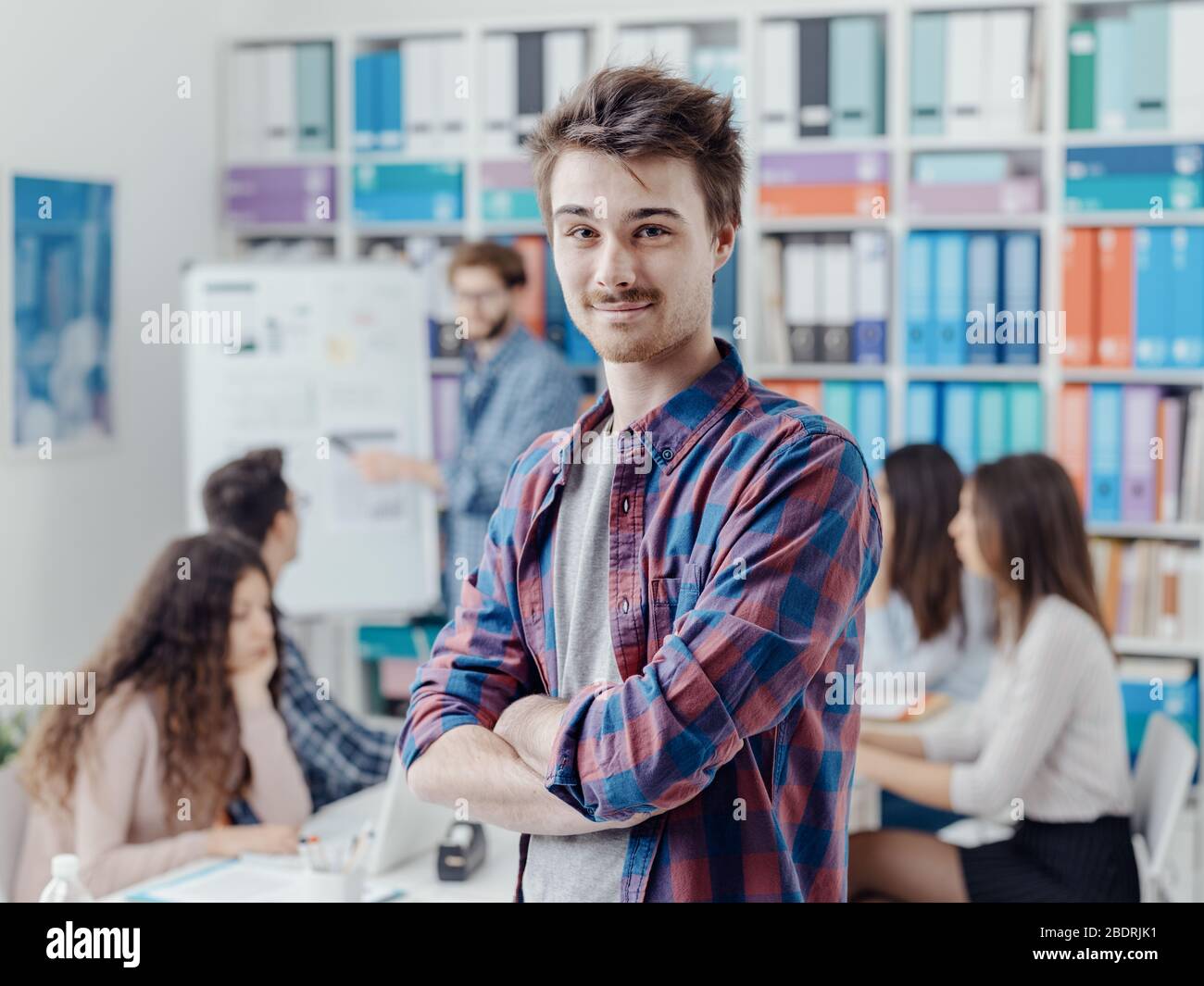 Gruppo di studenti universitari che si riuniscono e studiano insieme, uno studente sta posando e sorridendo in primo piano Foto Stock