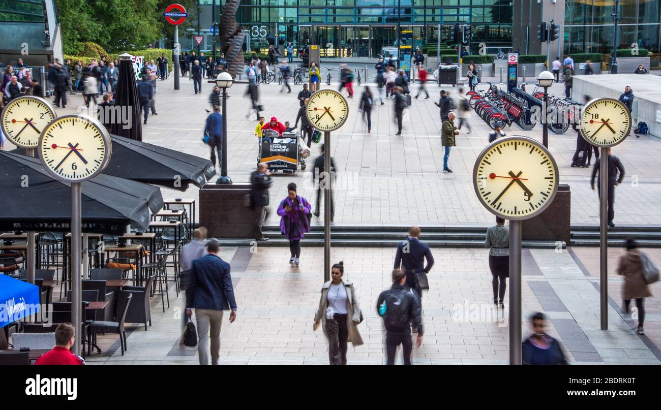 LONDRA- gli uomini d'affari camminano a Canary Wharf vicino all'iconica installazione dell'orologio, il quartiere finanziario di Londra Foto Stock