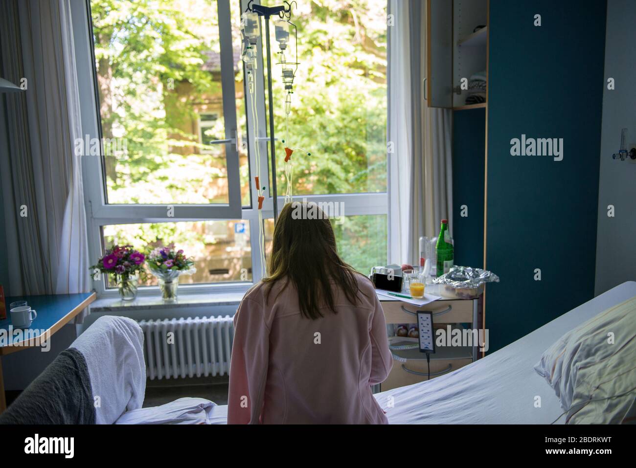 COVID-19. Giovane donna che rimane in un ospedale male con un catetere in mano, epidemia di coronavirus. Smartphone Covid per il monitoraggio dei pazienti Foto Stock
