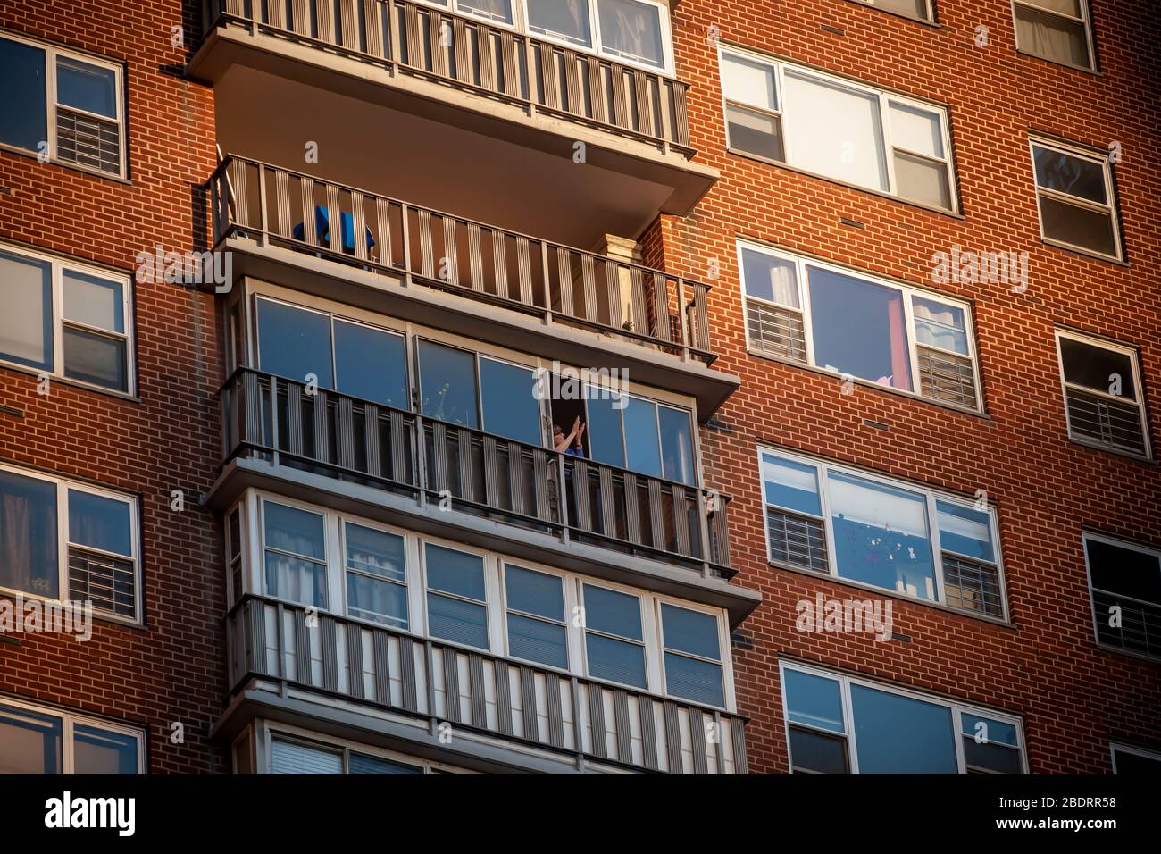 La gente applaude gli operatori sanitari dai loro balconi in un edificio di appartamenti a Chelsea a New York il mercoledì 8 aprile 2020. Alle 7:00 PM ogni notte i newyorkesi urlano, bang le pentole, fischietti di colpo, ecc. per fare il rumore per mostrare il loro sostegno agli operatori sanitari sulle linee anteriori nella pandemia di COVID-19. (© Richard B. Levine) Foto Stock