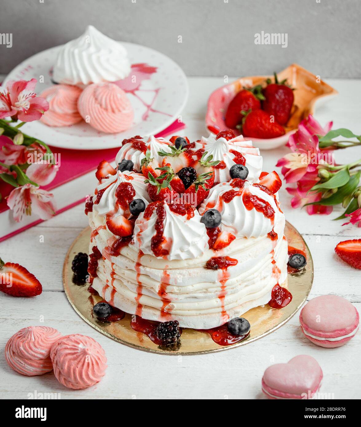 torta alla meringa alla bacche decorata con mirtillo e sciroppo di fragola Foto Stock