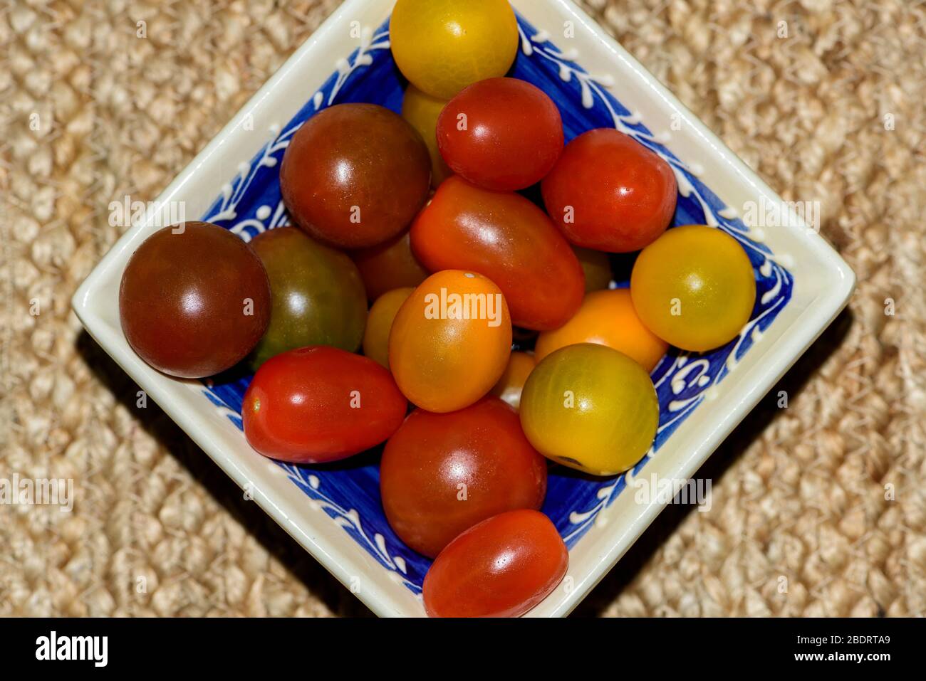 Ciotola quadrata riempita con vari colori di pomodori ciliegini Foto Stock