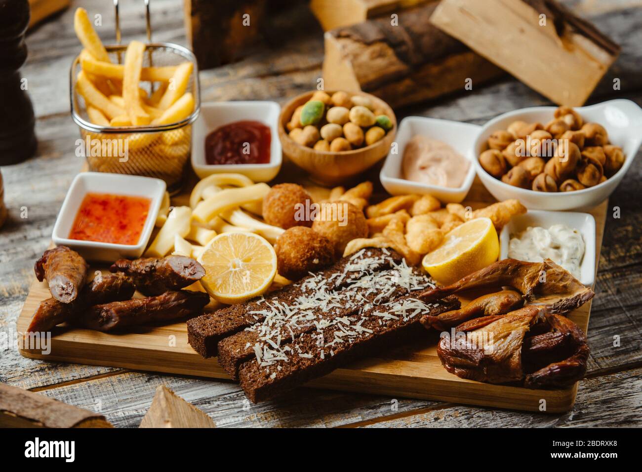 spuntini a piatto con ali affumicate salsicce patatine fritte, noci e salse Foto Stock