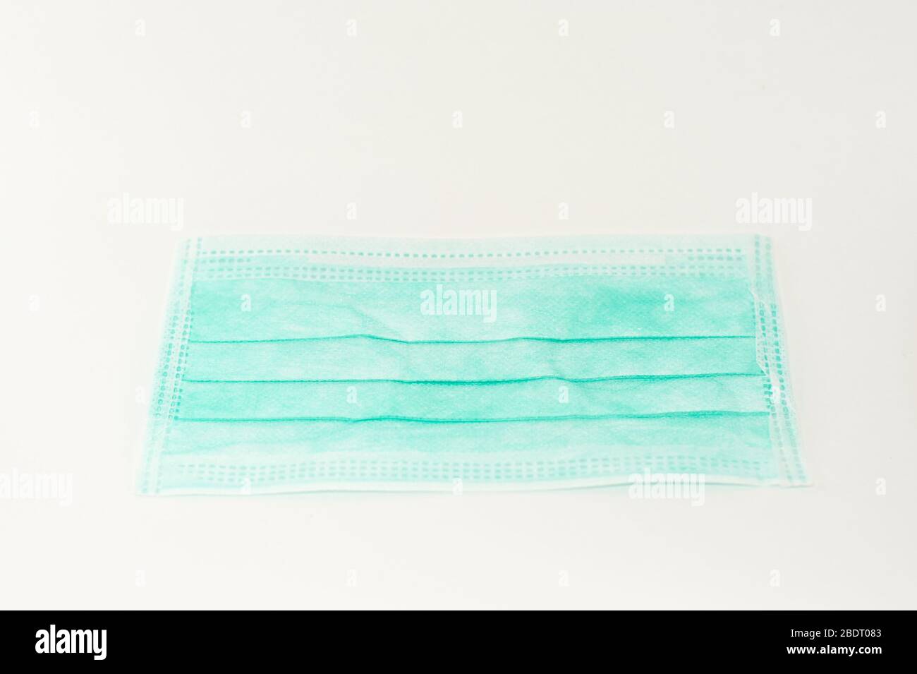 Maschera chirurgica per la protezione dal coronavirus. Protezione Covid-19. Maschera verde su sfondo bianco Foto Stock