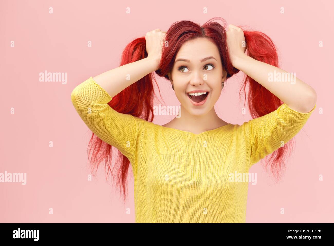 ragazza fa le facce tiene sopra ai capelli come la coda di ponytail Foto Stock