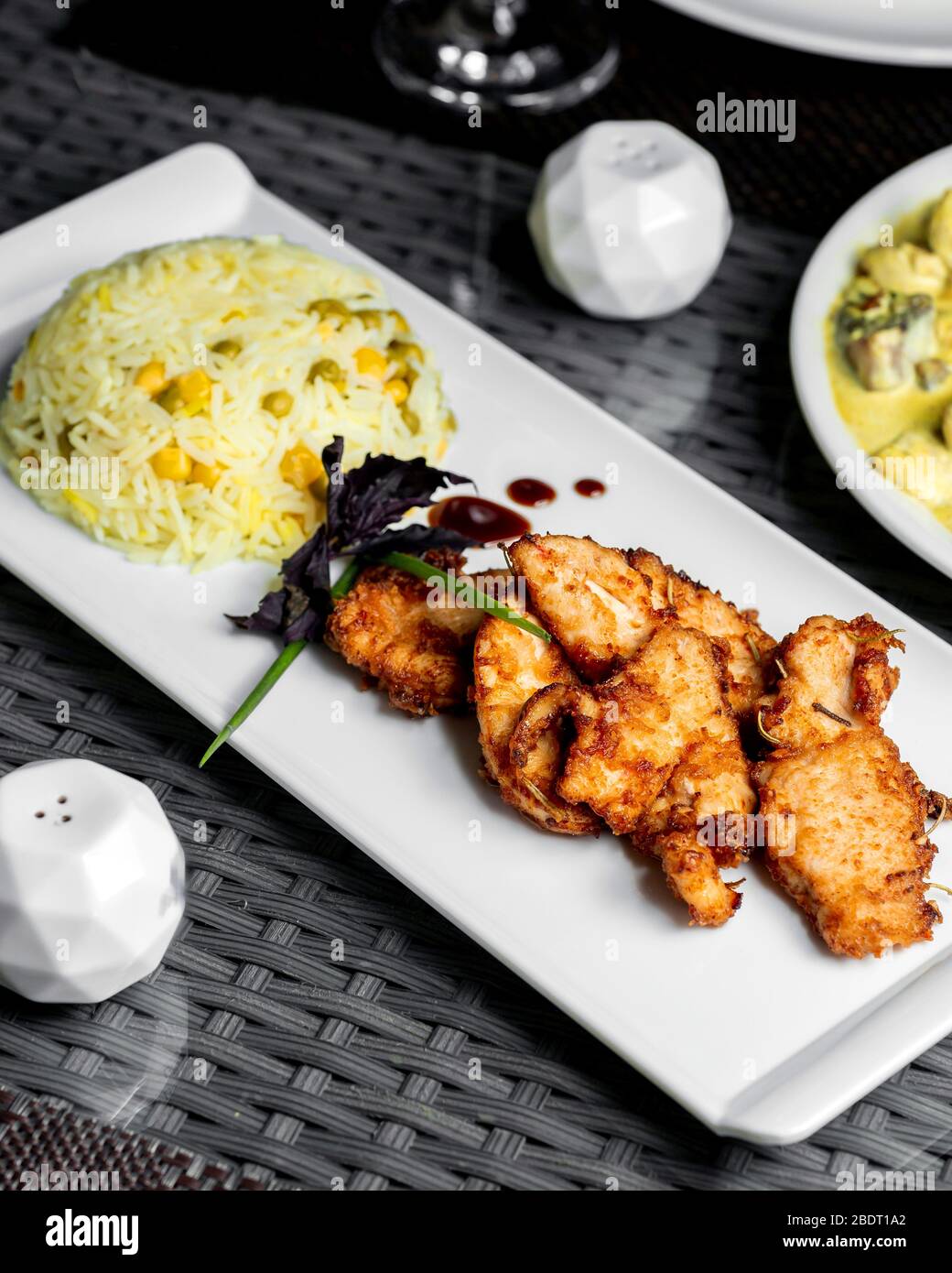 un piatto di riso con piselli servito con filetti di pollo fritti Foto Stock