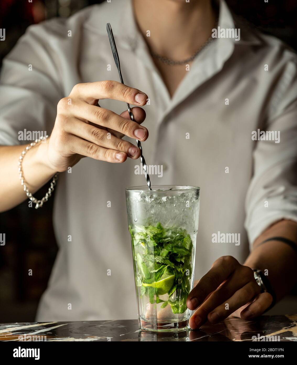 il barman mescola il cocktail mojito con il cucchiaio di metallo Foto Stock