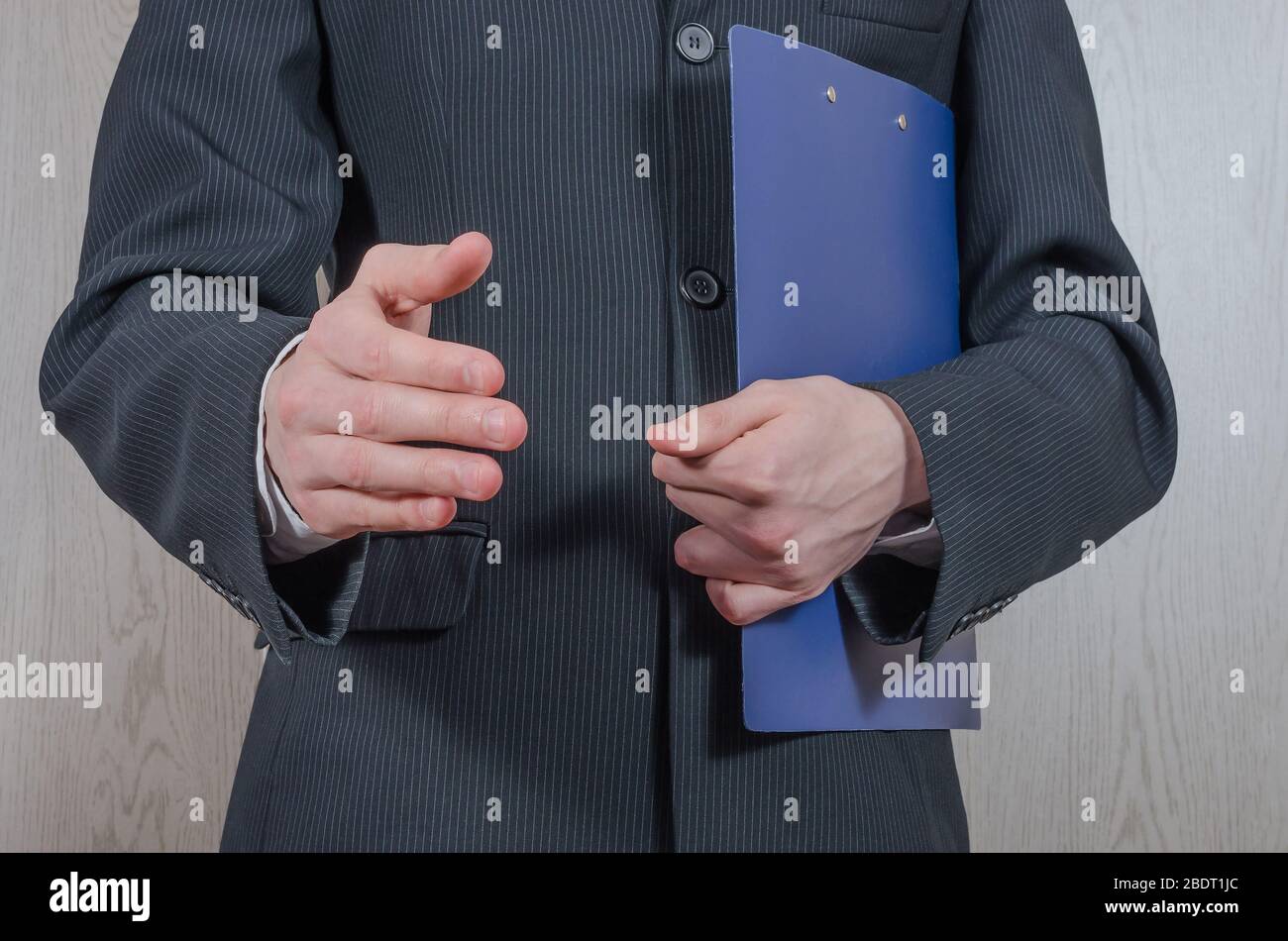 Un giovane in un vestito nero con una cartella tiene la mano per una stretta di mano. Proposta commerciale, partnership. Foto Stock