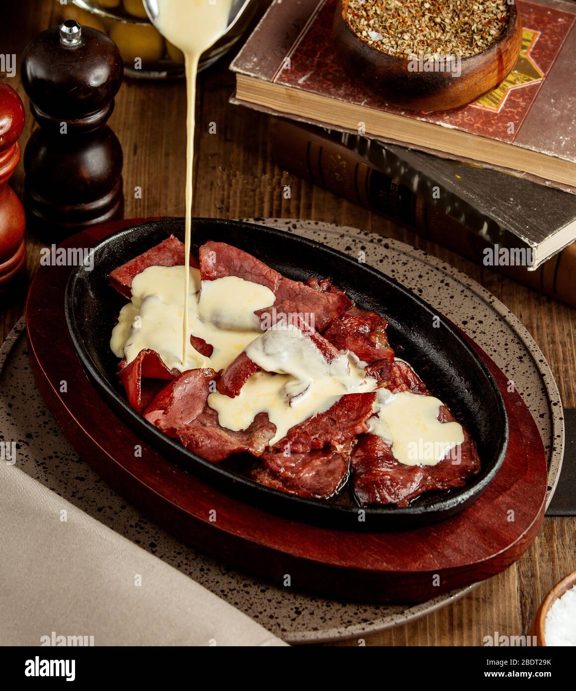 la crema viene versata sopra le fette di carne cotte crude Foto Stock