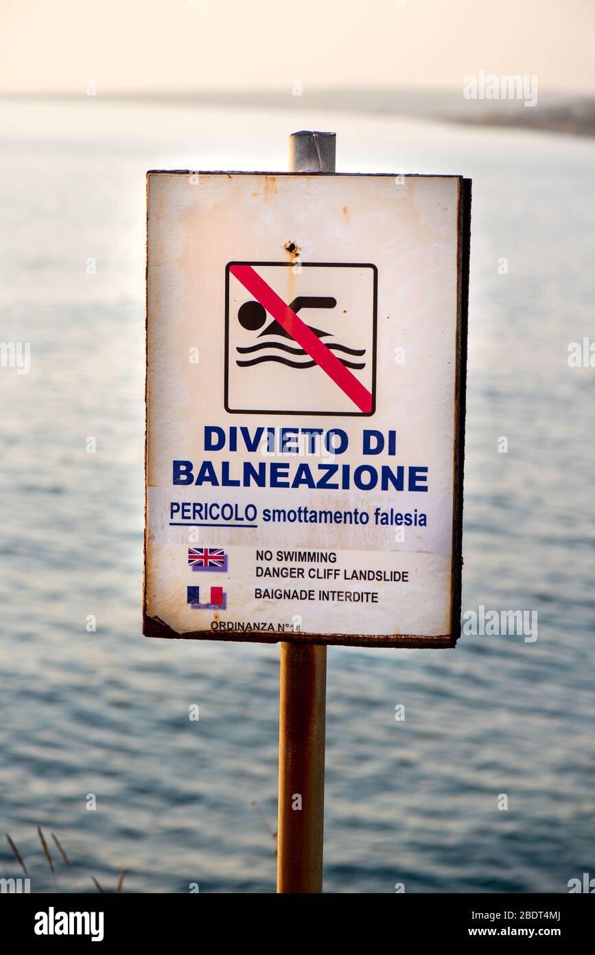 Primo piano del cartello "No Swimming Danger Cliff" in italiano, inglese e francese Foto Stock